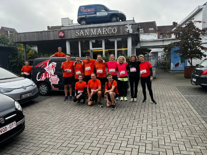 Teamfoto met rode outfits voor de ingang van San Marco